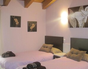 Une chambre avec deux lits, chacun doté d’une tête de lit, d’une table de chevet et d’œuvres d’art accrochées aux murs.