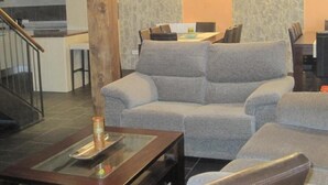 Ein Wohnzimmer mit grauem Sofa, einem Holztisch und einer Treppe.