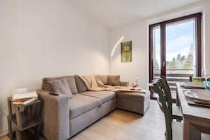 A modern living room with a sofa, a dining table, and a window with a view. - Apartment 'Casa Mia' with Mountain View, Private Garden and Wi-Fi (Prada)