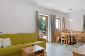 Una sala moderna con un sofá verde, una mesa de comedor de madera y sillas.