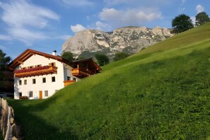 A white building with wooden balconies and a mountain backdrop.