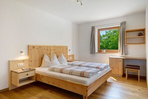 A bedroom with a wooden bed, bedside tables, a desk, and a window with a view of trees. - Apartment 'Völs' with Mountain View, Private Terrace and Wi-Fi (FIE' ALLO SCILIAR)