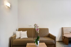 A living room with a brown sofa, a white cushion, a wooden coffee table, and a potted orchid. - Apartment 'Völs' with Mountain View, Private Terrace and Wi-Fi (FIE' ALLO SCILIAR)