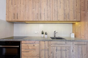 A kitchen with wooden cabinets, a granite countertop, a dishwasher, and a sink. - Apartment 'Völs' with Mountain View, Private Terrace and Wi-Fi (FIE' ALLO SCILIAR)