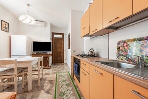 A compact kitchen with a dining area, a television, and a patterned backsplash.