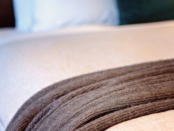 A close-up of a textured fabric, possibly a blanket or a piece of clothing, with a blurred background suggesting a domestic setting.