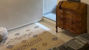 Una habitación con una escalera, un aparador de madera, un tapete estampado y un cuadro en la pared.