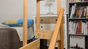 A bedroom with a wooden bed frame, a bedside table with a lamp, a bookshelf, and a wall-mounted shelf with books. - Small and cozy studio apartment in Florence (Florence)