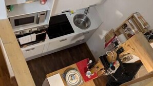 A compact kitchen with a microwave, stove, sink, and a small dining area with a red tray. - Small and cozy studio apartment in Florence (Florence)