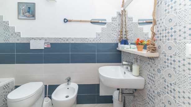 A bathroom with two toilets, a bidet, a sink, and a mirror. - Guest House 'La Camera Della Stella Marina' with Mountain View, Wi-Fi and Air Conditioning (Palau)