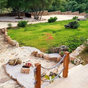 A landscaped garden with a stone pathway, a small pond, and a wooden fence.