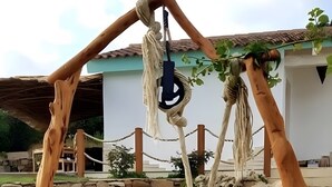 Un espacio al aire libre rústico con una estructura de madera, un muro de piedra y una olla de metal.