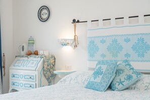 Une chambre à coucher comprenant un lit, une commode, une petite table et une étagère fixée au mur.