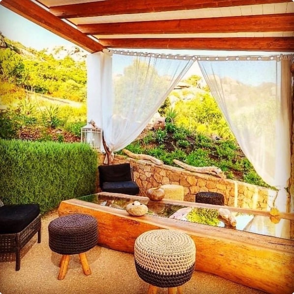 Un espace extérieur accueillant, avec un mur en pierre, une table en verre et des meubles en osier.