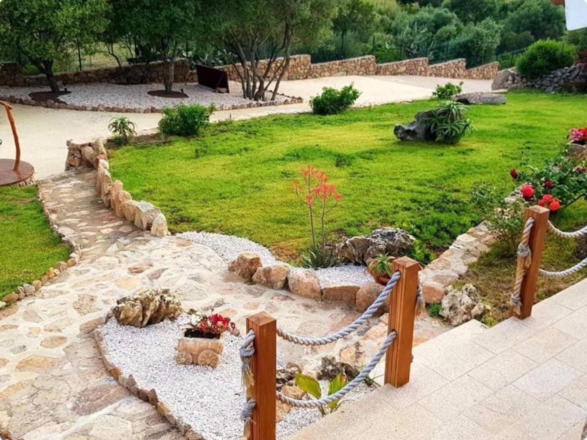 A stone pathway leading to a grassy area with a small garden and a seating area.