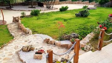 A stone pathway leading to a grassy area with a small garden and a seating area.