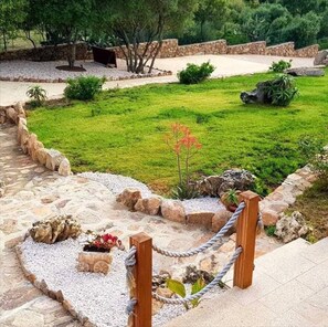 Un jardín ajardinado con un sendero de piedra, un pequeño estanque y una cerca de madera.
