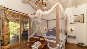 Un lit à baldaquin à quatre poteaux, avec une chaise en bois et une petite table placée à côté.