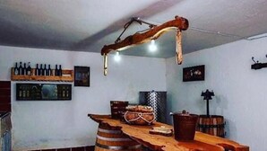 Un coin bar au style rustique, avec des tonneaux en bois, un luminaire suspendu et un porte-bouteilles fixé au mur.