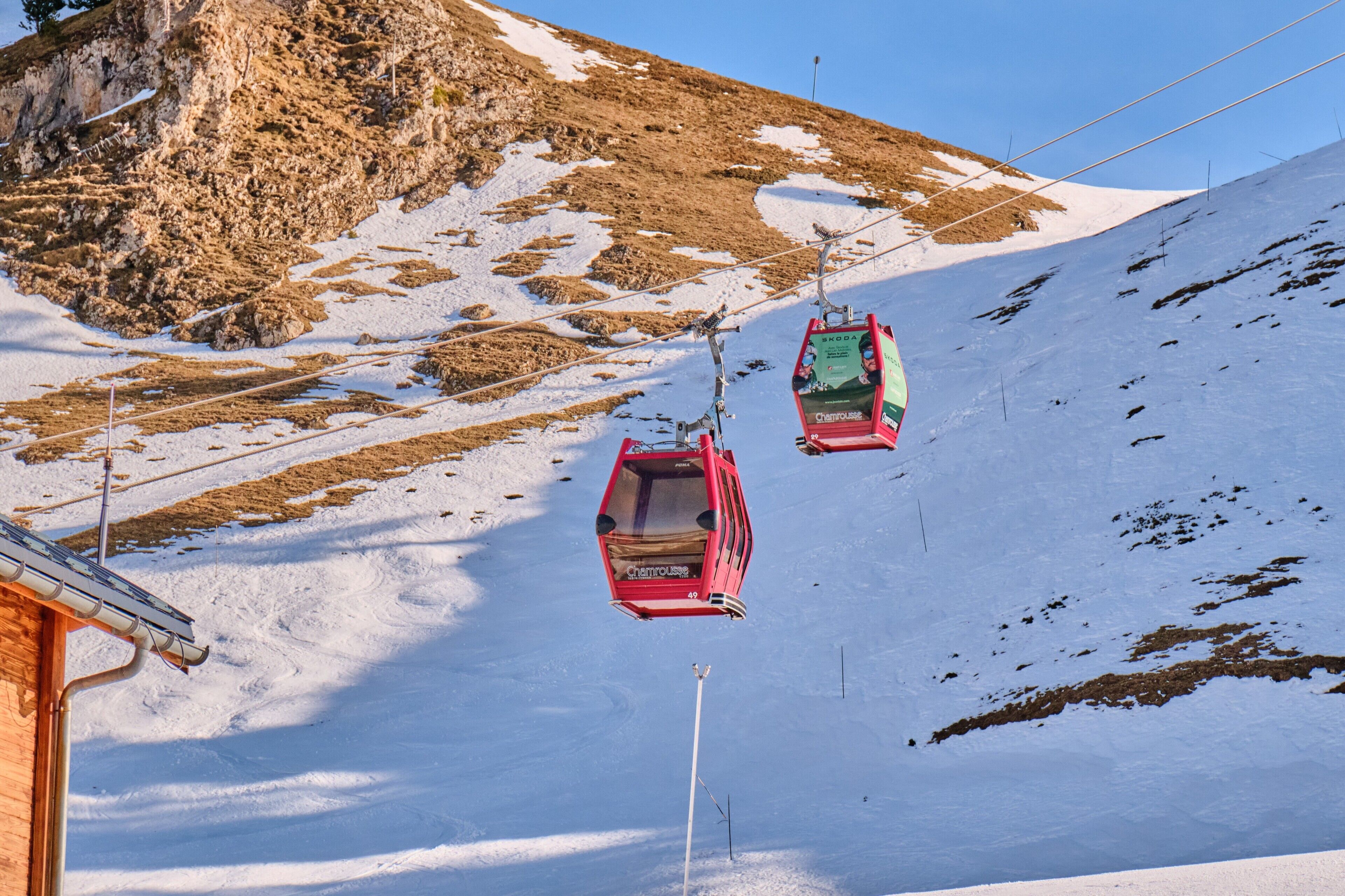 A ski lift with cabins moving up a snowy slope.