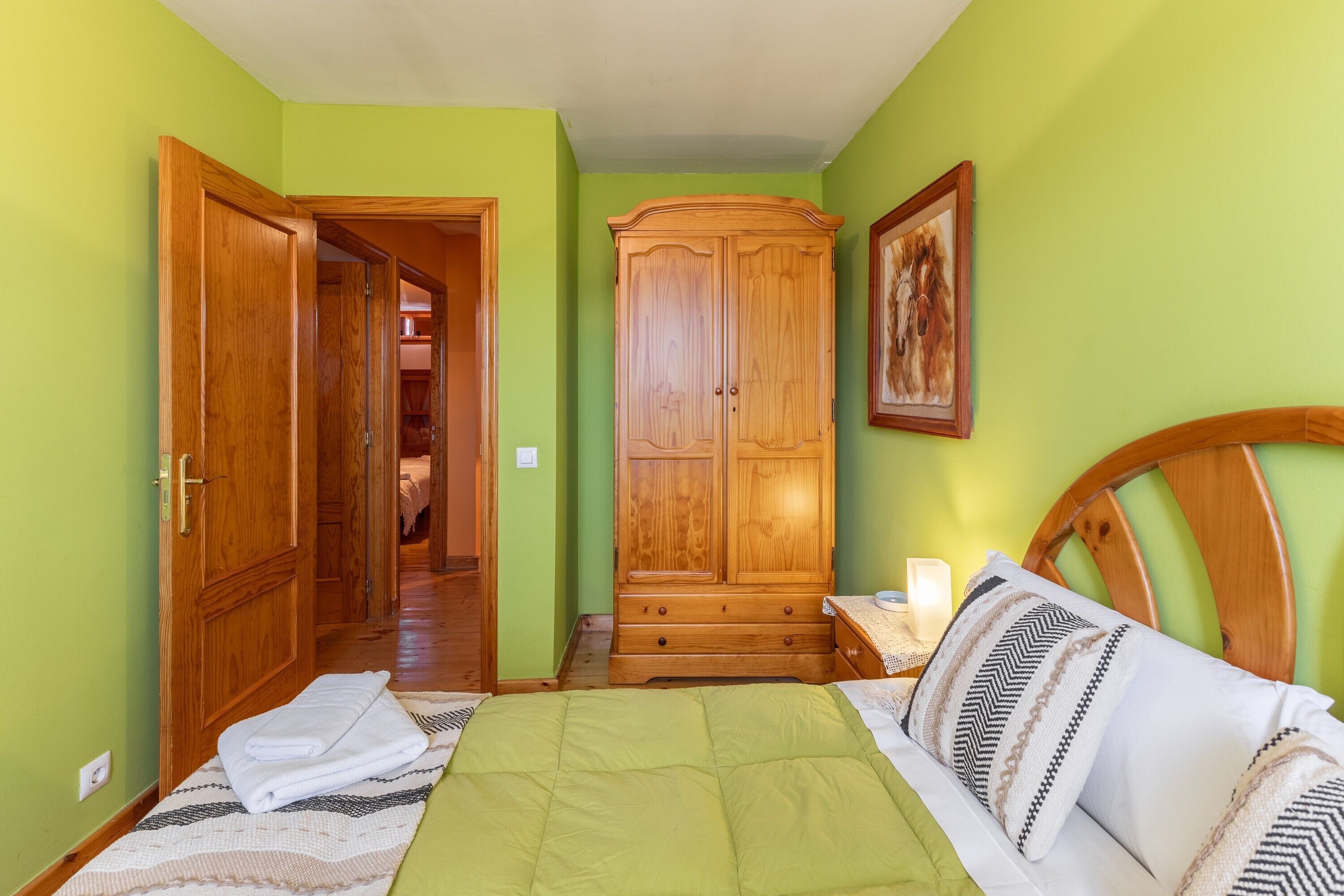 Ein Schlafzimmer mit einem Bett, einem Holzschrank und einer Tür zu einem anderen Raum.