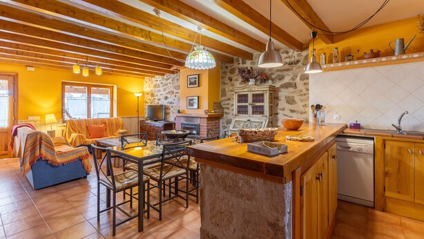 A cozy interior with a dining area, kitchen, and a fireplace.