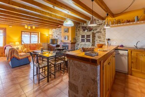 Un intérieur chaleureux comprenant un coin repas, une cuisine et une cheminée.