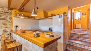 A kitchen with a wooden island, a refrigerator, and a stone wall.