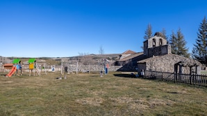 A playground with swings and slides, a stone building with a bell tower, and a fenced area.