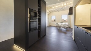 Eine moderne Küche mit integrierten Geräten, ein Essbereich mit Tisch und Stühlen sowie ein Blick auf die Stadt durch große Fenster.