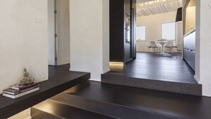 Ein modernes Interieur mit Treppe, Essbereich mit Stühlen und Tisch sowie Küchenzeile mit Schränken und Kühlschrank.