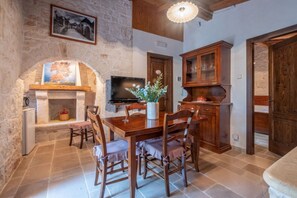 A rustic dining area with a stone fireplace, wooden table, and chairs.