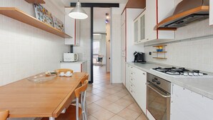 Een moderne keuken met een houten eettafel, stoelen, een fornuis en een magnetron.
