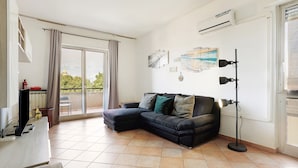 Een woonkamer met een hoekbank, een vloerlamp en kunstwerken aan de muur.