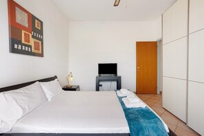 A hotel room with a bed, a TV, a wardrobe, and a wall art piece.