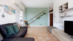 Een woonkamer met een bank, een televisie, een boekenkast en een ladder tegen de muur.