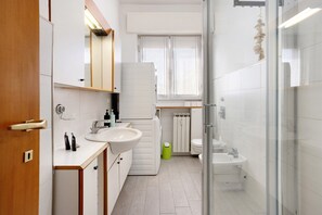 A modern bathroom with a sink, mirror, toilet, and shower area.