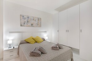 Un dormitorio con cama, mesitas de noche, un cuadro y un armario.