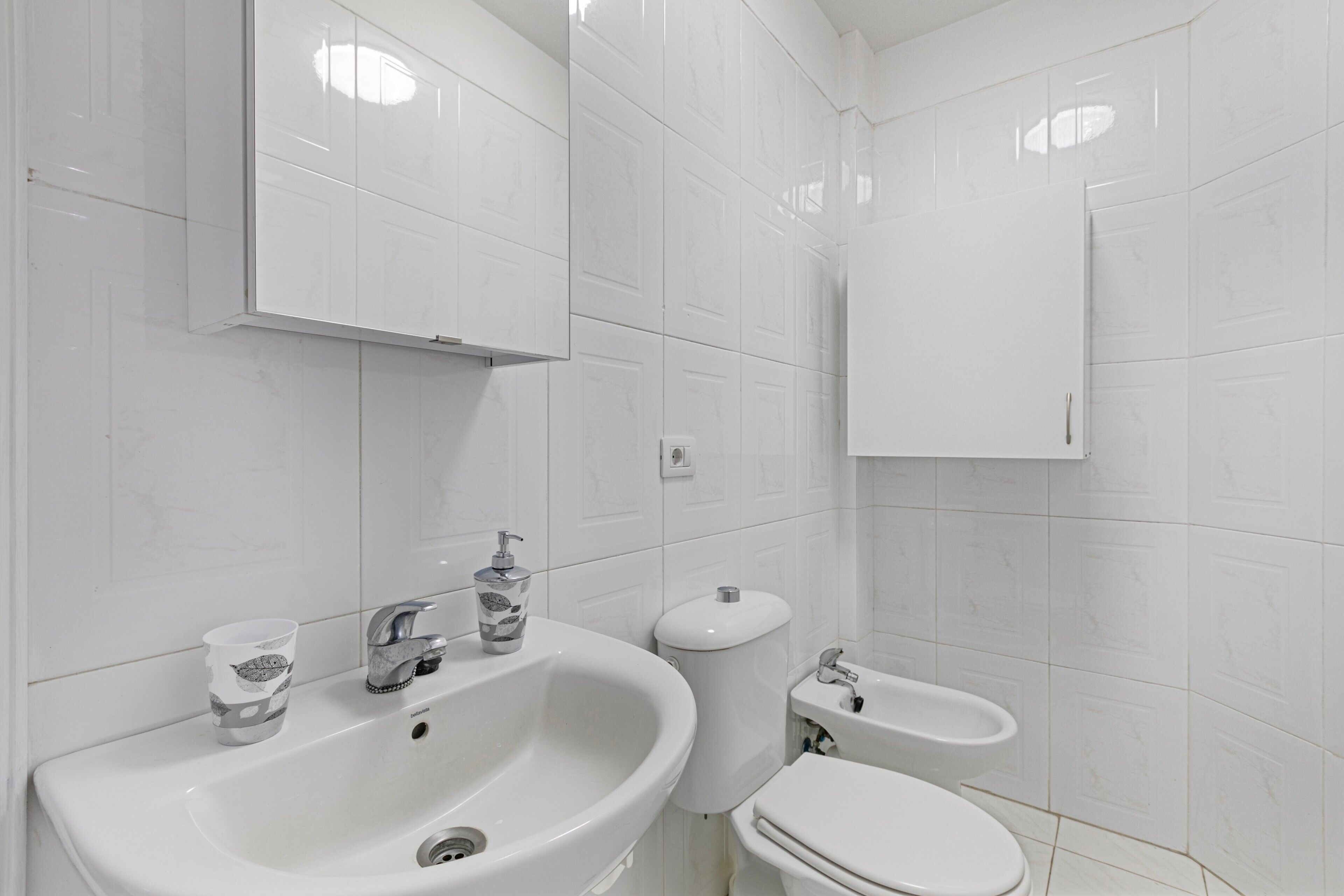 A bathroom with a sink, toilet, bidet, and mirror.