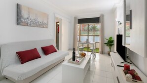Una sala de estar moderna con un sofá, una mesa de centro, un televisor de pantalla plana y un cuadro en la pared.