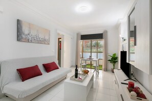 A modern living room with a sofa, a coffee table, a flat-screen TV, and a painting on the wall.