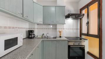 A kitchen with a microwave, coffee maker, sink, stove, and cabinets.