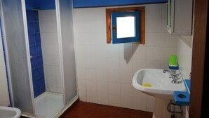 A bathroom with a shower, a sink, and a window.