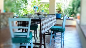 An outdoor covered patio with a table set for two, chairs, and potted plants.
