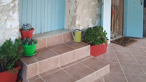 A building with blue doors, potted plants, and a weathered wall.