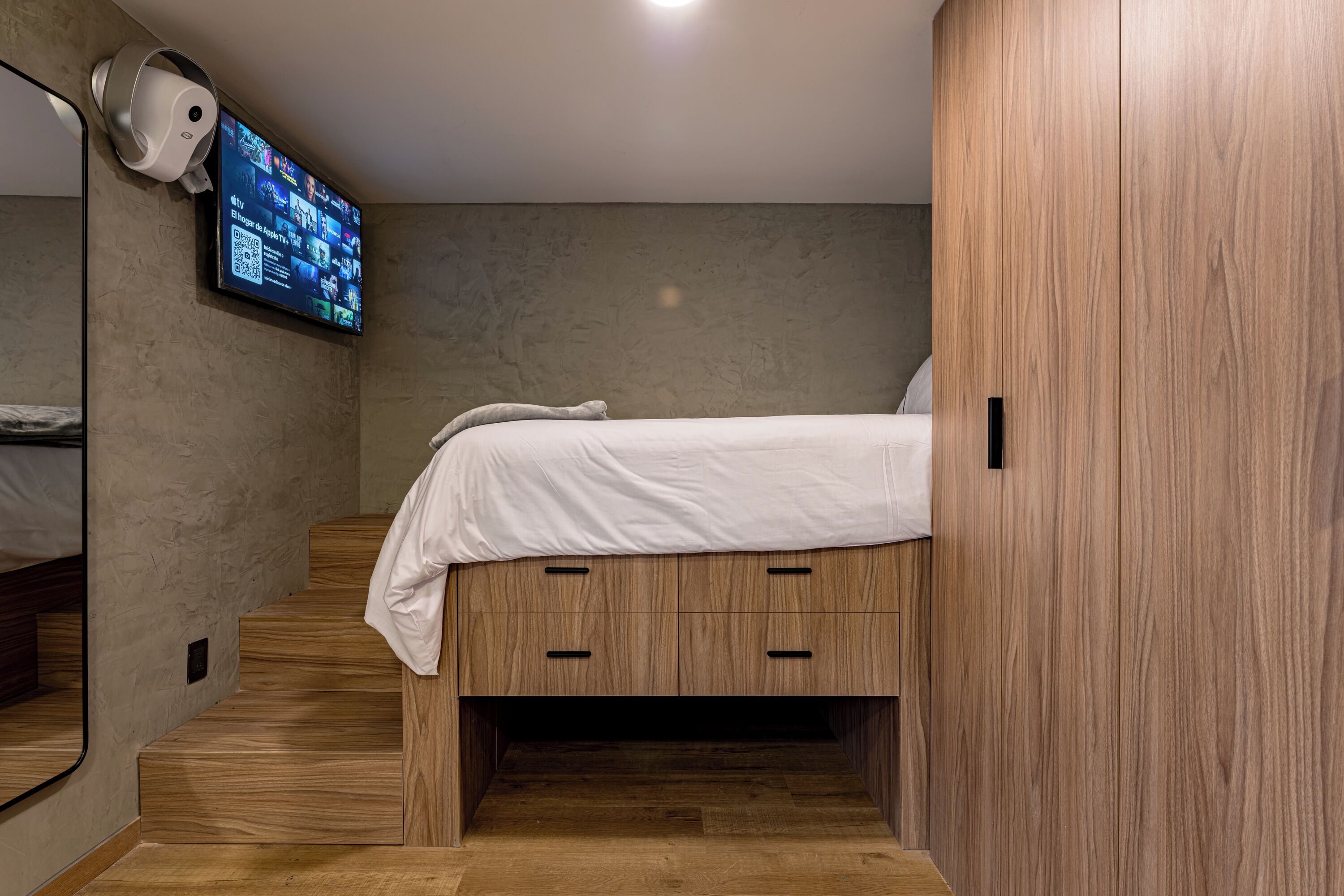 Una camera da letto con un letto, una TV a parete e un armadio in legno.