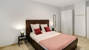 Ein Schlafzimmer mit Bett, Nachttischen, einem Kleiderschrank und einem Spiegel.