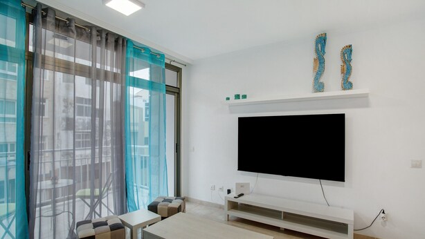Ein Wohnzimmer mit Flachbildfernseher, Couch und Couchtisch.