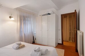 A bedroom with a bed, a wardrobe, a radiator, and a door with curtains.