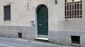 A building with a green door, a barred window, and a small step leading to the entrance.